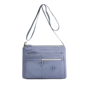 Trendy women's nylon cross-body bag with multiple zip compartments and water-repellent finish.