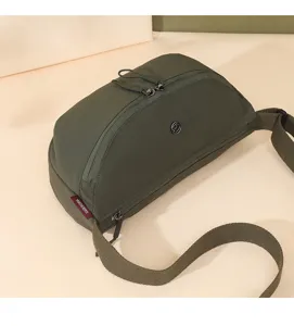 Detailed view of the dark green lightweight nylon crossbody bag, showing durable zippers and strap.