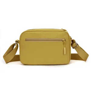 Yellow nylon crossbody bag detail, casual shoulder bag with front zipper pocket and strap.