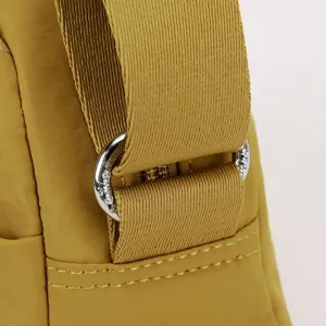 Detail of yellow nylon crossbody bag strap, durable hardware ring and sturdy webbed strap.
