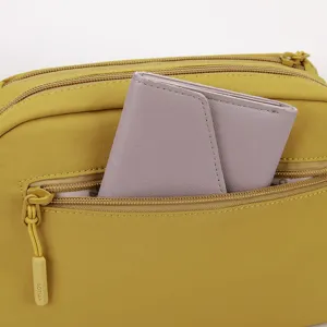 Detailed shot of casual women nylon crossbody bag in yellow with purple wallet inside pocket.
