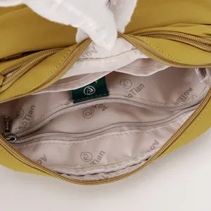 Nylon shoulder bag interior detail, showing multi-zipper pocket design and lining.