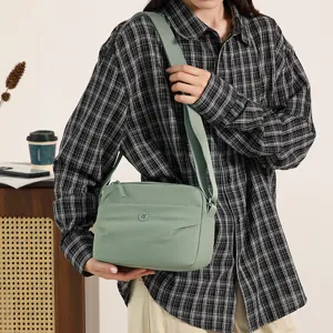 Detailed close-up shot of the casual light green nylon crossbody bag, showing smooth fabric.