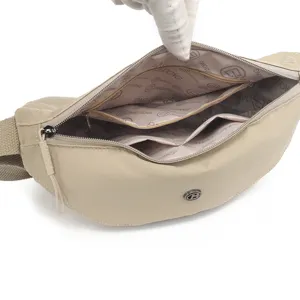 Detailed view of the beige nylon crossbody bag interior, featuring multiple zipper pockets.