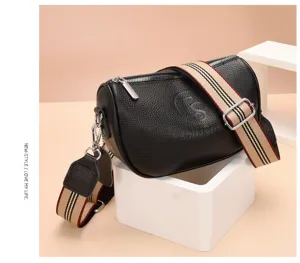 Borsa a tracolla cilindrica in pelle nera vista dettagliata con ampia cinghia a righe e fibbie.