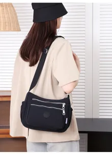 Black nylon crossbody bag with multi zippers, front pocket and adjustable wide shoulder strap.