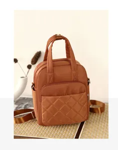 Brown nylon backpack detail shot, stylish quilted daypack with top handle and adjustable straps.