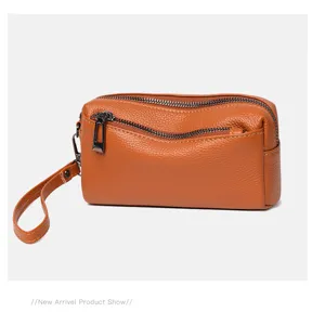 Detailed close-up view of the brown genuine leather wristlet purse with dual zippers.