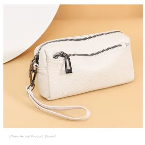 Detailed view of genuine leather women clutch bag, showing dual zipper and wrist strap design.