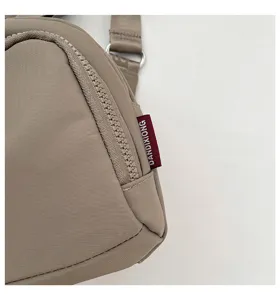 Detailed close-up of lightweight nylon crossbody bag zipper and side brand label design.