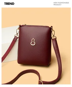 Maroon small crossbody phone bag with gold gourd pendant, stylish leather shoulder bag detail view.
