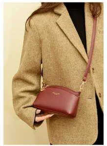 Elegant wine red dome crossbody bag for women, stylish leather shoulder bag with gold hardware.