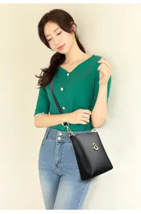 Detail shot of a black PU leather crossbody phone bag with a stylish golden gourd pendant.
