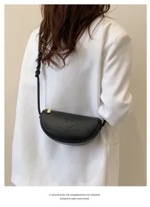 Detail view of black leather crescent crossbody bag worn by model, simple and stylish.