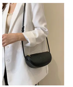 Close-up view of a stylish black leather crescent shoulder bag showcasing fine texture.