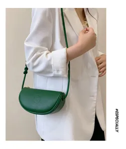 Minimalist leather half moon shoulder bag detail showcasing smooth dark green cowhide texture.