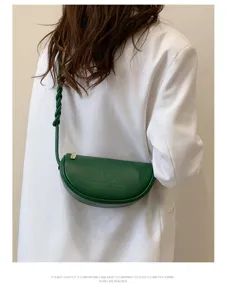 Green leather crescent crossbody bag detail, stylish woven strap daily fashion accessory.