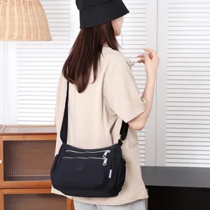 Detail view of black nylon crossbody shoulder bag, multi pocket design with zippers.