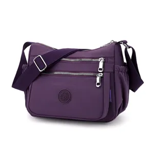 Purple nylon crossbody bag detail showcasing multi-pocket compartments and adjustable strap.