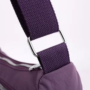 Purple nylon crossbody bag detail close up showing durable shoulder strap and metal hardware.