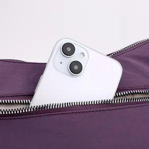 Purple nylon shoulder bag detail shot showing exterior zipper pocket with phone storage capacity
