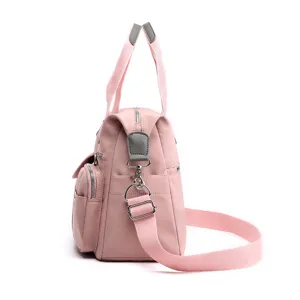 Zijaanzicht detail van een roze nylon handtas met meerdere vakken en verstelbare schouderriem.