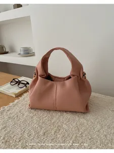 Detailed shot of pink ruched cloud shoulder bag in minimalist lifestyle setting, elegant style.