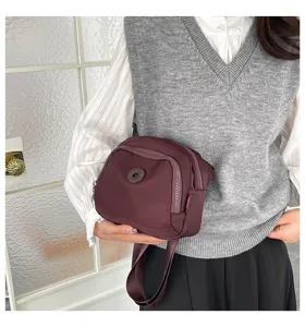 Detailed view of the dark red nylon crossbody bag, featuring multiple zippers and practical design.