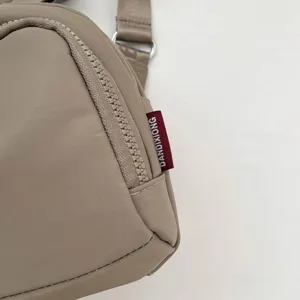 Detailed view of lightweight nylon crossbody shoulder bag, casual everyday commuter shell bag style.