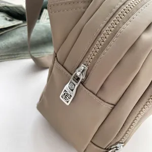 Close-up detail shot of casual nylon crossbody bag metal zipper and durable fabric texture.