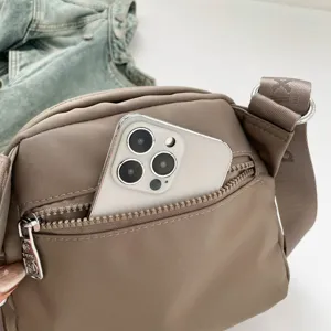 Nylon crossbody bag detail showing front zipper pocket and strap craftsmanship, casual everyday use.