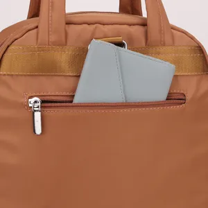 Detailed view of casual brown nylon backpack featuring a convenient zippered pocket and wallet.