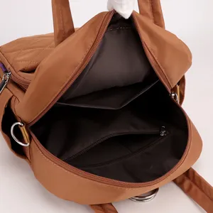 Brown nylon quilted backpack interior detail showing zipper pocket and spacious main compartment.
