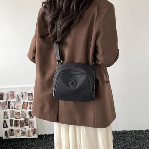 Detail view of the black nylon crossbody bag, showcasing casual daily wear and metal hardware.