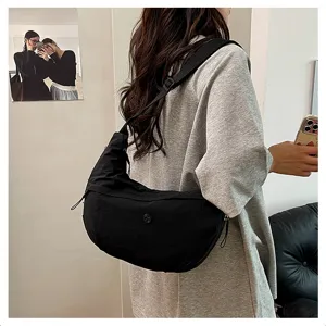 Detail view of a minimalist black crescent crossbody bag, lightweight waterproof nylon.