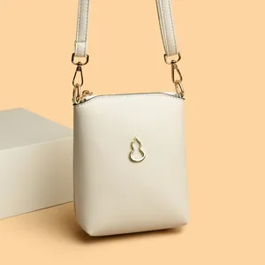 Minimalist off-white vertical crossbody phone bag with gold gourd hardware and chic leather strap.