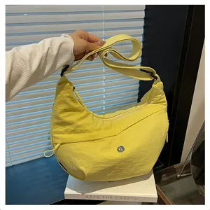 Close-up detail view of yellow nylon hobo shoulder bag featuring a wide strap and zip pocket.