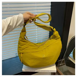 Detailed view of yellow waterproof nylon crescent crossbody shoulder bag in minimalist setting.