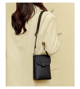 Bolso bandolera vertical negro vista detallada, textura de cuero graneado con correa fina.