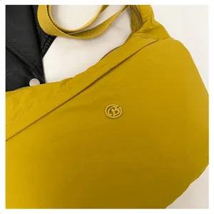 Close-up detail of yellow waterproof nylon crossbody dumpling bag showing texture and logo.