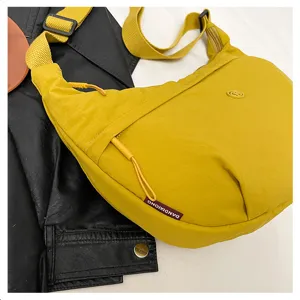 Close-up of yellow nylon crossbody bag, lightweight waterproof crescent shoulder bag detail.