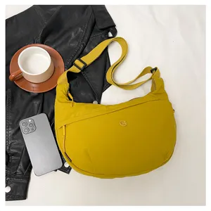 Detail view of the yellow nylon crescent shoulder bag lifestyle display with props.