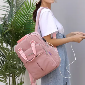 Close-up of stylish pink travel backpack with USB charging port worn by model outdoors.