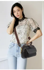 Detail view of a chic black multi-layer leather crossbody bag with a wide brown strap.