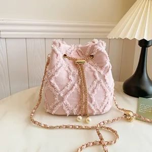 Pink denim bucket bag with chain strap and fringe design, stylish shoulder crossbody bag.