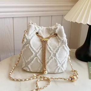 White quilted denim bucket bag with gold chain strap, chic shoulder crossbody handbag detail.