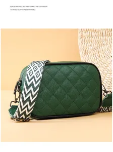Close-up detail of green quilted leather crossbody bag with wide geometric pattern strap.