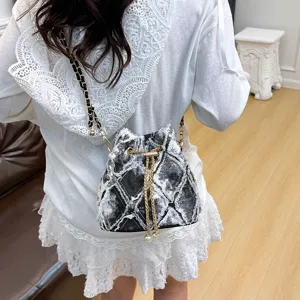 Detail view of the stylish quilted denim bucket bag featuring chain strap and pearl details.