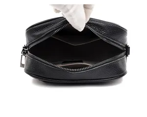 Black leather crossbody bag interior detail view, zipper closure, premium texture design.