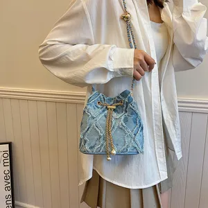 Detailed view of the stylish denim bucket bag featuring chain strap and pearl drawstring design.